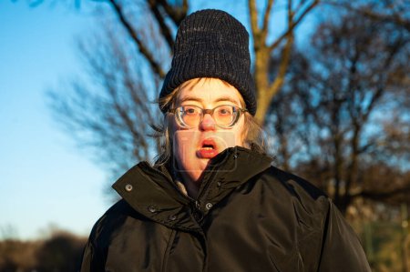 Foto de 40 year old worried white woman with the Down Syndrome, wearing a hat and a winter jacket, Tienen, Flanders, Belgium - Imagen libre de derechos