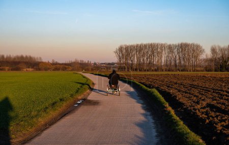 Foto de Woman with Down Syndrome driving the tricycle during a colorful winter landscape during the golden hour, Tienen, Flanders, Belgium - Imagen libre de derechos