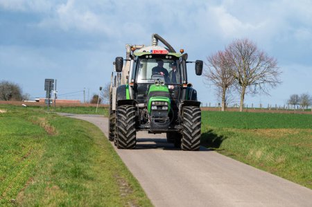 Téléchargez les photos : Merchtem, Région flamande du Brabant, Belgique, 25 février 2023 - Grande machine tracteur conduite du champ - en image libre de droit