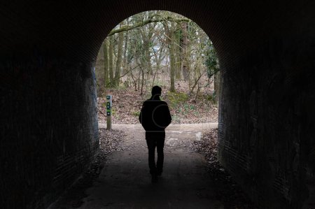 Photo for Uccle, Brussels Capital Region, Belgium, March 4, 2023 - Lonely man walking under an arched bridge - Royalty Free Image
