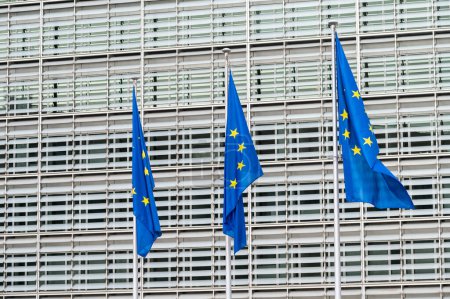 Foto de Barrio Europeo de Bruselas, Bélgica - 15 de marzo de 2023 - Tres banderas europeas con el edificio Berlaymont al fondo - Imagen libre de derechos