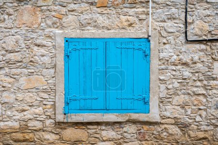 Foto de Lofou, Limassol District, Chipre, 24 de marzo de 2023 - Muro de ladrillo texturizado y persianas azules - Imagen libre de derechos