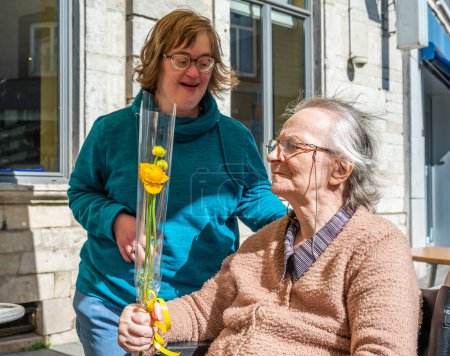 Foto de Retrato familiar de una mujer de 40 años con Síndrome de Down dando una flor a su madre de 84 años, Tienen, Bélgica - Imagen libre de derechos