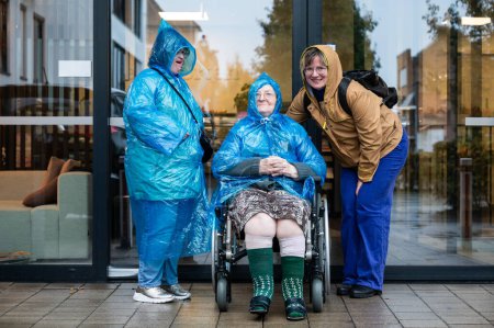 Téléchargez les photos : Portrait de famille d'une femme de 41 ans atteinte du syndrome de Down, d'une grand-mère en fauteuil roulant et d'une femme de 37 ans portant des vêtements de pluie, Tienen, Belgique - en image libre de droit