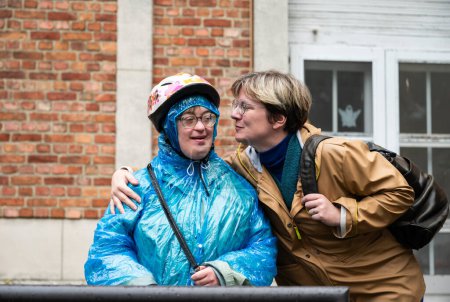 Téléchargez les photos : Joyeux moment entre une femme de 41 ans avec un poncho de pluie bleu ayant le syndrome de Down et son amie de 37 ans, Tienen, Flandre, Belgique - en image libre de droit