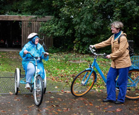 Téléchargez les photos : 41 ans avec le syndrome de Down assise sur un tricycle avec son amie de 37 ans sur un vélo en plein air, Tienen, Flandre, Belgique - en image libre de droit