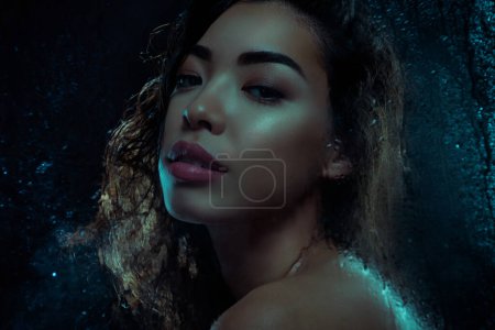Téléchargez les photos : Photo rapprochée d'une femme magnifique jouissant d'une hygiène de bain nocturne isolée sur fond sombre avec des gouttelettes d'eau de pluie. - en image libre de droit