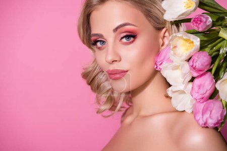 Téléchargez les photos : Superbe fille mannequin studio portrait posant sur des tulipes décorées toile de fond lumineux maquillage isolé rose fond pastel. - en image libre de droit