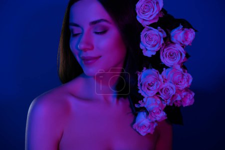 Foto de Atractiva modelo de moda mujer tiene rosas flores en los ojos de peinado cerrado azul rosa oscuro efecto de luz fondo de neón. - Imagen libre de derechos