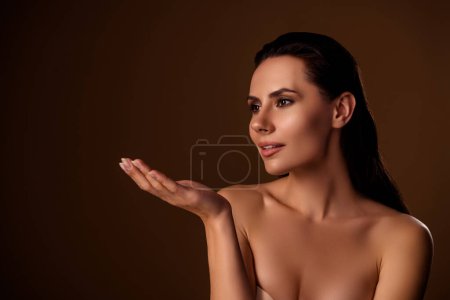 Photo for Charming lady model nude body hold open palm presenting new beauty product advert choice isolated brown background. - Royalty Free Image