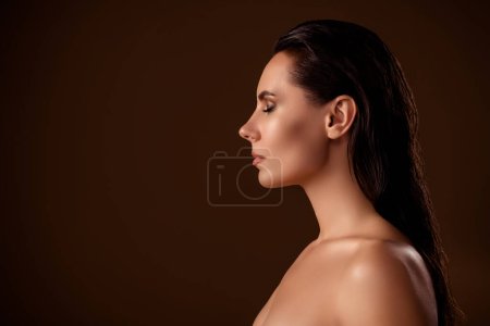Foto de Cerrar perfil retrato hermosa joven con soporte de pelo húmedo en el salón de estudio solarium spray marrón fondo. - Imagen libre de derechos