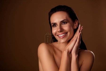 Foto de Atractivo modelo de mujer con el pelo mojado mantener los brazos juntos bronceado en la piel facial salón solarium aislado fondo marrón. - Imagen libre de derechos