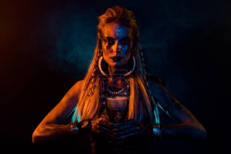 Portrait of fantasy valkyrie woman make demonic ritual hold potion cup orange lights isolated on black background.