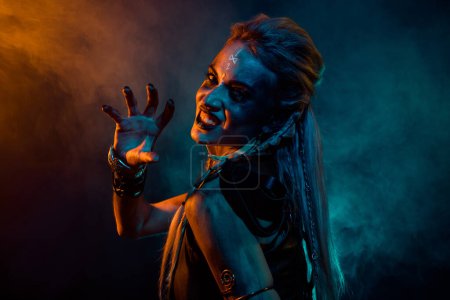 Téléchargez les photos : Photo de profil de impitoyable furieux valkyrie femme sourire dents bras peur orange bleu lumières isolées sur fond sombre. - en image libre de droit