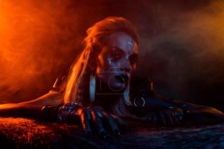 Foto de Retrato de aterradora valquiria mujer de guerra miedo luces rojas niebla brumosa aislado sobre fondo oscuro colorido. - Imagen libre de derechos