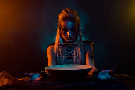 Foto de Retrato de mujer misteriosa vikinga arte corporal preparar poción rezar oden naranja azul luces aisladas sobre fondo oscuro. - Imagen libre de derechos