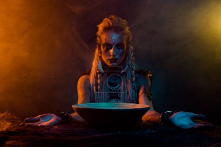 Foto de Retrato de mujer druida vikinga interactuar espíritus de otro mundo demoníaco ritual naranja luz aislada sobre fondo oscuro. - Imagen libre de derechos