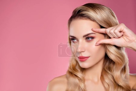Photo for Photo of attractive lady touch eye applying anti aging laser correction isolated on pastel color background. - Royalty Free Image