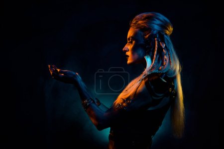 Foto de Foto de señora misteriosa salvaje usar ropa vikinga rezando demonios aislados naranja oscuro color azul fondo. - Imagen libre de derechos