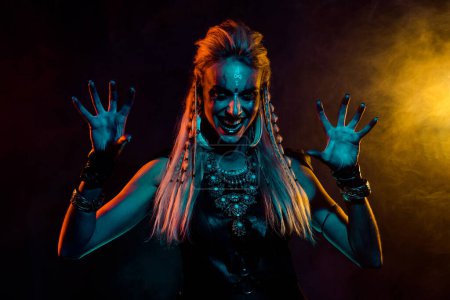 Photo for Photo of dangerous valkyrie woman evil laugh arms fingers scare foggy mist orange light isolated on black background. - Royalty Free Image