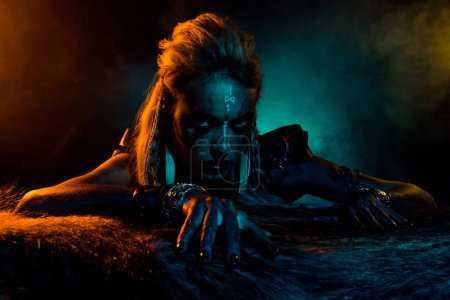 Foto de Retrato de la aterradora mitología del norte vikinga niña azul amarillo luces niebla animal muerto piel aislada sobre fondo oscuro. - Imagen libre de derechos