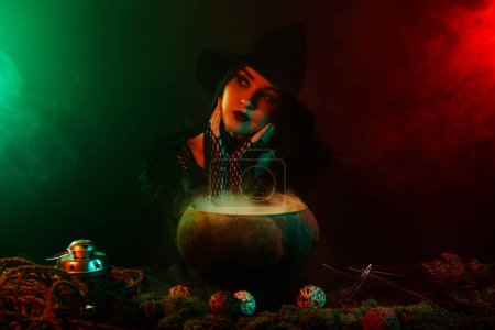 Photo for Photo of dreamy witch cooking boiling cauldron love potion for enchant prince over mist neon background. - Royalty Free Image