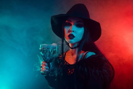 Photo for Photo of devil dark witch prepare spooky ritual poisonous elixir with mist over colorful neon background. - Royalty Free Image