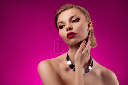 Téléchargez les photos : Photof de élégante dame chic toucher le visage en appliquant des ombres à paupières cosmétiques pour la date du jeu de rôle sur fond de couleur rose. - en image libre de droit