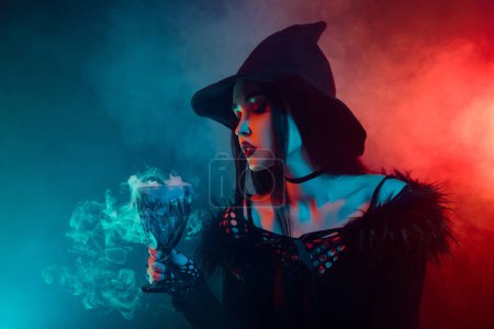 Foto de Foto de la poderosa señora bruja poción de cocina ritual de amor místico líquido en la noche de Halloween sobre fondo de neón niebla. - Imagen libre de derechos