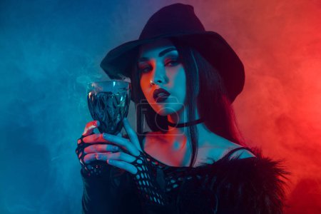 Photo for Photo of dark witch warlock hold glass with poisonous liquid magical ritual over neon mist background. - Royalty Free Image