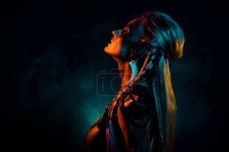 Foto de Foto de atractiva dama misteriosa fresca usar ropa vikinga rezando dioses de la muerte aislado fondo de color azul anaranjado. - Imagen libre de derechos