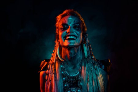 Foto de Foto de loca dama misteriosa enojada usar ropa vikinga riendo aislado humo naranja oscuro fondo. - Imagen libre de derechos