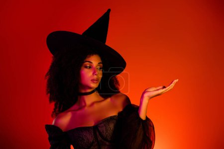 Foto de Foto de la poderosa dama bruja encantada haciendo hechizo ritual demostrar halloween oferta de eventos temáticos sobre fondo rojo. - Imagen libre de derechos
