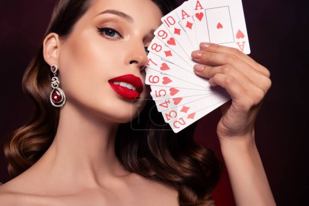Foto de Foto de la elegante dama repartidor jugando en el club de póquer mostrar su tarjeta de ganar fortuna sobre fondo oscuro. - Imagen libre de derechos