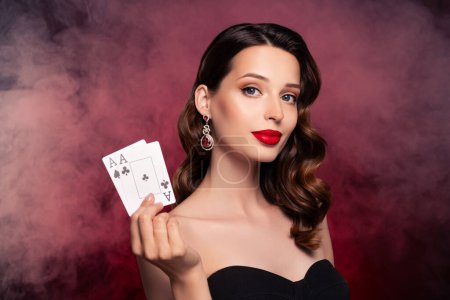 Foto de Foto de rica dama rica con clase muestran dos cartas ganadoras combinación de póquer sobre fondo oscuro niebla. - Imagen libre de derechos