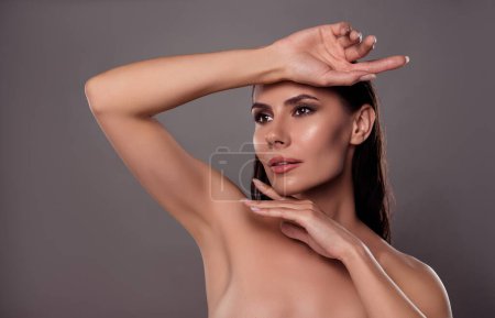 Foto de Foto retrato de atractiva joven mujer tacto cara manos spa salón aislado sobre fondo de color gris oscuro. - Imagen libre de derechos