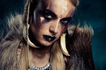 Foto de Foto de escudo doncella diosa vikinga usar antiguos dientes de lobo de piel de animal sobre fondo oscuro brumoso. - Imagen libre de derechos