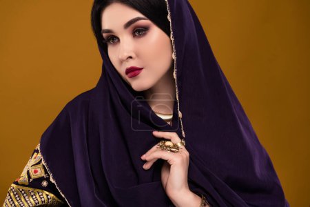 Téléchargez les photos : Photo de magnifique dame arabe attrayante bedouin porter costume national pour Voyage le long des déserts fond pastel. - en image libre de droit