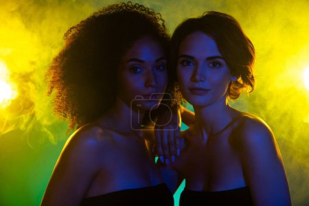 Photo for Photo of two tender girls best friends enjoy weekends in modern nightclub with shine mist neon lights. - Royalty Free Image
