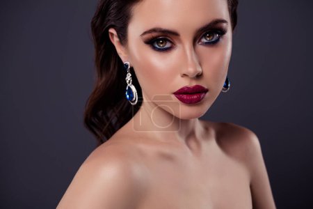 Photo for Portrait of stunning model with red pomade girlfriend advertise blue vintage earrings isolated on gray color background. - Royalty Free Image