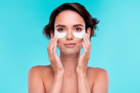 Photo for Photo of attractive lady touch under eye patch apply new morning routine for perfect facial skin over blue background. - Royalty Free Image
