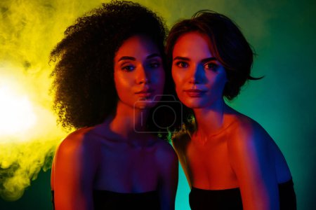 Téléchargez les photos : Photo de deux filles élégantes célèbrent les week-ends dans une boîte de nuit moderne avec fond effet néon brume. - en image libre de droit