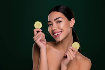 Photo for Photo of gorgeous asian young lady hold cucumber slices spa salon shoulders off isolated dark green color background. - Royalty Free Image