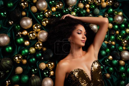Photo for Studio portrait of luxury model lady posing lying on silk texture background decorated with new year glitter baubles. - Royalty Free Image