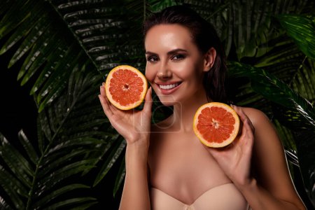Photo for Photo of tempting adorable woman naked shoulders holding two grapefruit halves outdoors tropical forest. - Royalty Free Image