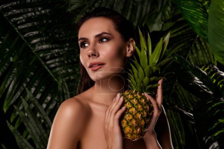 Téléchargez les photos : Photo d'une femme souriante rêveuse aux épaules nues tenant en plein air une forêt tropicale d'ananas doux violé. - en image libre de droit