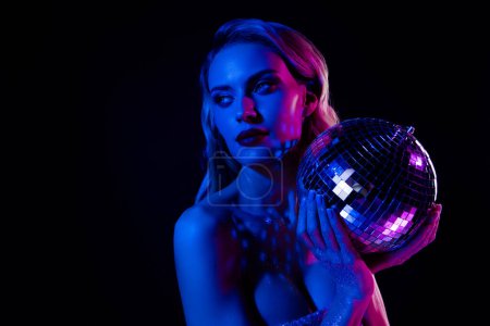 Téléchargez les photos : Photo de magnifique dame tenir paillettes boule disco profiter de la danse moderne sur fond fluorescent néon. - en image libre de droit