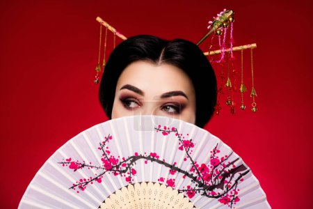 Photo for Photo of elegant japanese lady hold sakura flowers fan look up empty space isolated on red gradient color background. - Royalty Free Image
