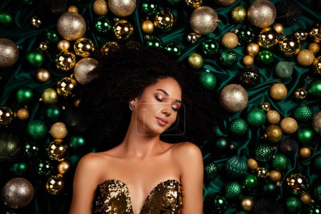 Téléchargez les photos : Vue de dessus portrait studio de belle dame tendre fermant les yeux couché entre luxe arbre de Noël doré boules brillantes. - en image libre de droit