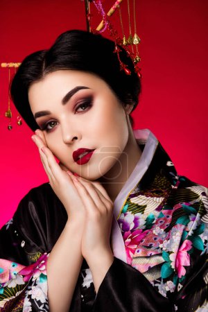 Photo for Vertical photo of gorgeous korean lady two arms touch cheeks dressed costume visage isolated on red color background. - Royalty Free Image